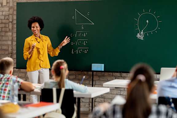 A teacher in a yellow shirt is teaching a math class.