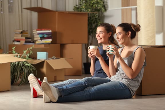two young women sitting on the floor drinking coffee and looking at each other at Altis Grand Lake Willis, Orlando, 32821
