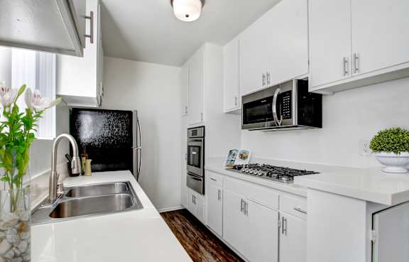 A kitchen with white cabinets and a black fridge.