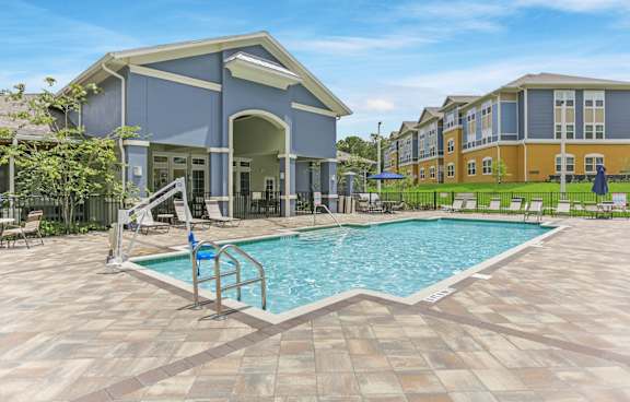 A swimming pool in front of a building with a blue sky in the background.