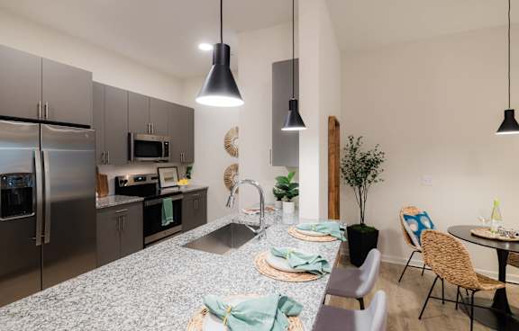 A modern kitchen with a dining table set for two at Hudson at Renaissance Apartments, North Carolina 28405