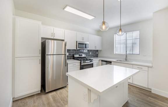 A modern kitchen with a white island and stainless steel appliances.