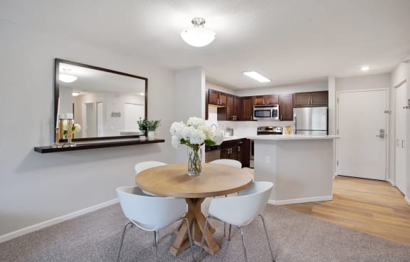 a dining room with a table and chairs and a kitchen with a mirror
