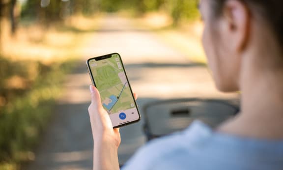 a woman sitting in a car holding up a cell phone with a map on it