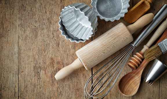 a bunch of whisks and utensils on a wooden table
