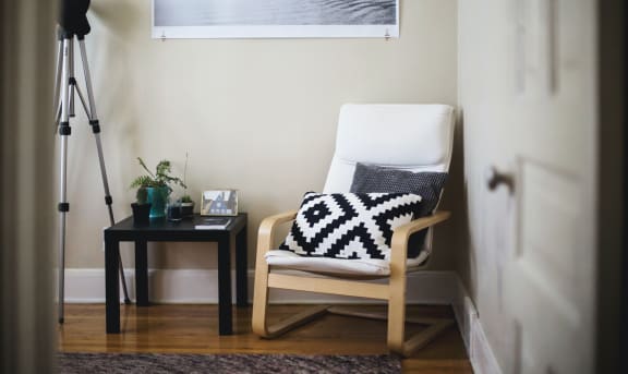 White chair in corner next to table and camera stand