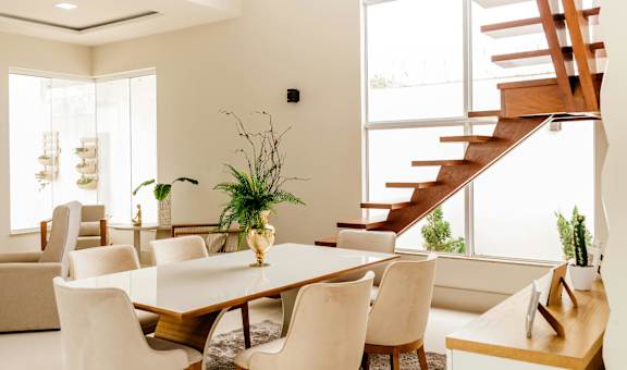 A dining room with a wooden table and white chairs.