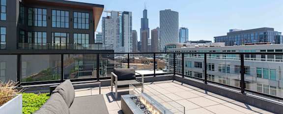 A rooftop patio with a couch and a fire pit.