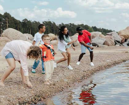 A group of people are playing by the water at The Villages Apartment of Bayan Grove in Boynton Beach, FL