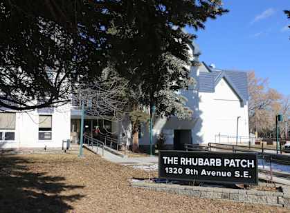 A white building with a sign that says "The Rhubarb Patch" in front of it.