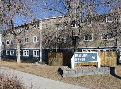 A sign that says Hamilton Manor is in front of a building.