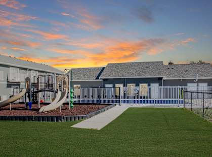 A playground with a slide and a building in the background.