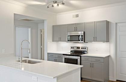 A modern kitchen with a white countertop and stainless steel appliances.