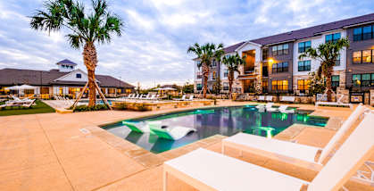 a swimming pool with two white chairs and a building in the background at The Parker Austin, Pflugerville, 78660