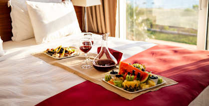 a bed with a tray of food and wine on it