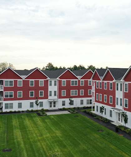A large red and white building with a green lawn in front.