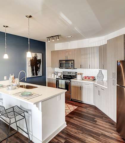 A kitchen with a white island and a stainless steel refrigerator at The Linden Apartments, Davidson, NC, 28036
