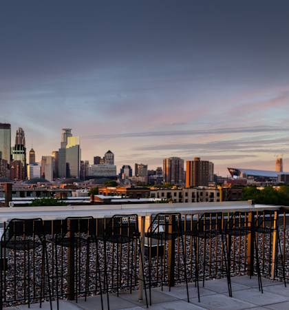 A cityscape view from a rooftop bar with empty tables and chairs.