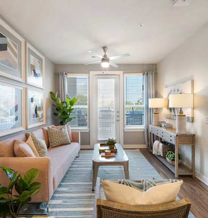 A well-lit living room with a sofa, a chair, and a potted plant.