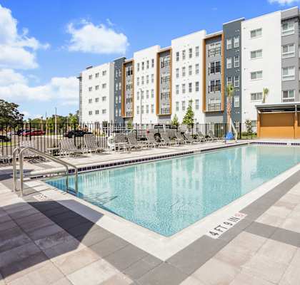 a swimming pool with chaise lounge chairs and a building in the background