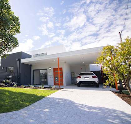A modern house with a white car parked in the driveway.