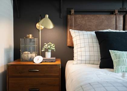 a bedroom with a bed and a nightstand with a clock and a lamp on