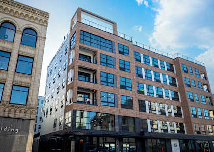A modern building with a glass facade stands next to an older building with arched windows at The Gallery Apartment Homes Apartments, Allentown, PA, 18101