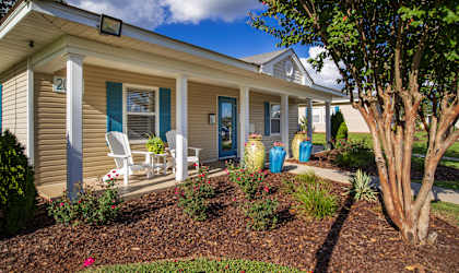 a home with a porch and a tree in the front yard