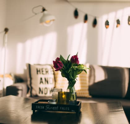 a book on a table with a vase of flowers and a couch in the background
