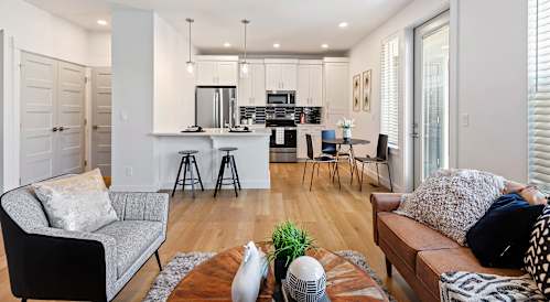 a living room and kitchen area with white walls and hardwood floors at Alante Homes at Lake Hazel, Boise, Idaho