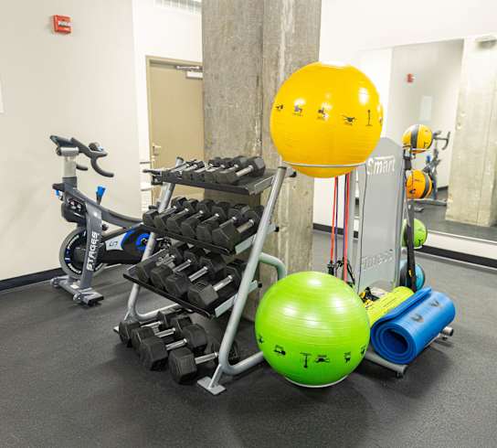 a fitness room with weights and a yellow ball in the middle of it