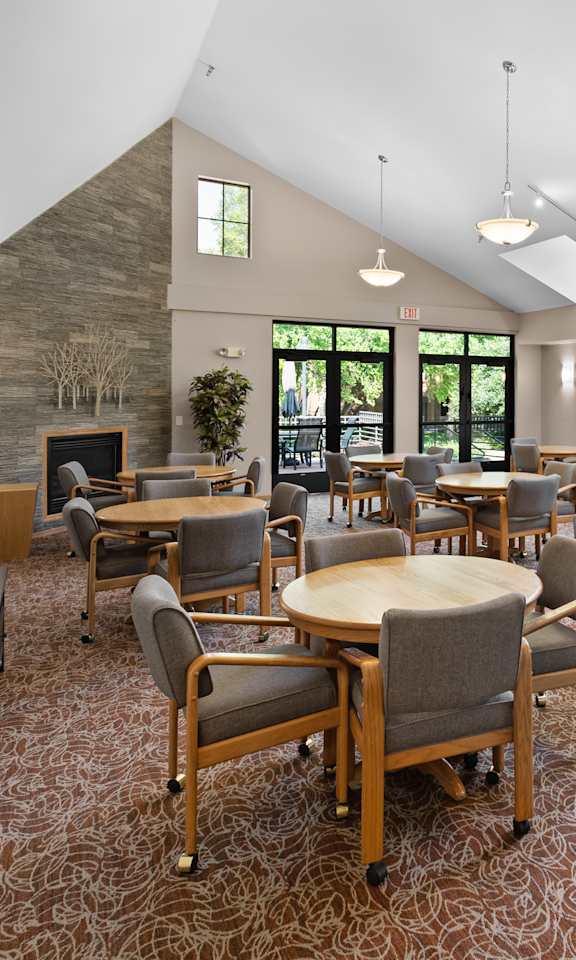 A room with tables and chairs and a stone wall.