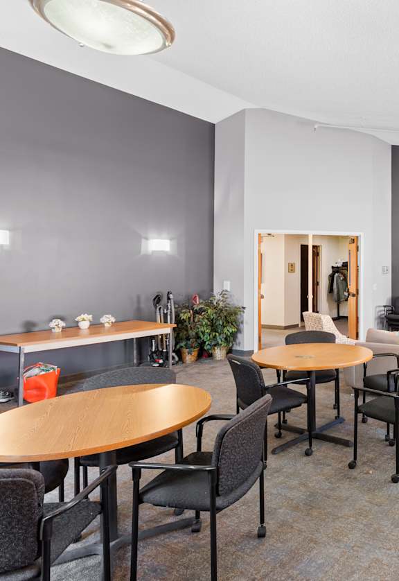 A room with grey walls and a carpeted floor has a table and chairs in it.