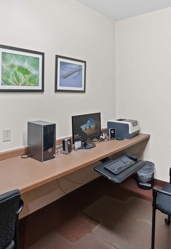 A room with a desk, two chairs, and a computer setup.