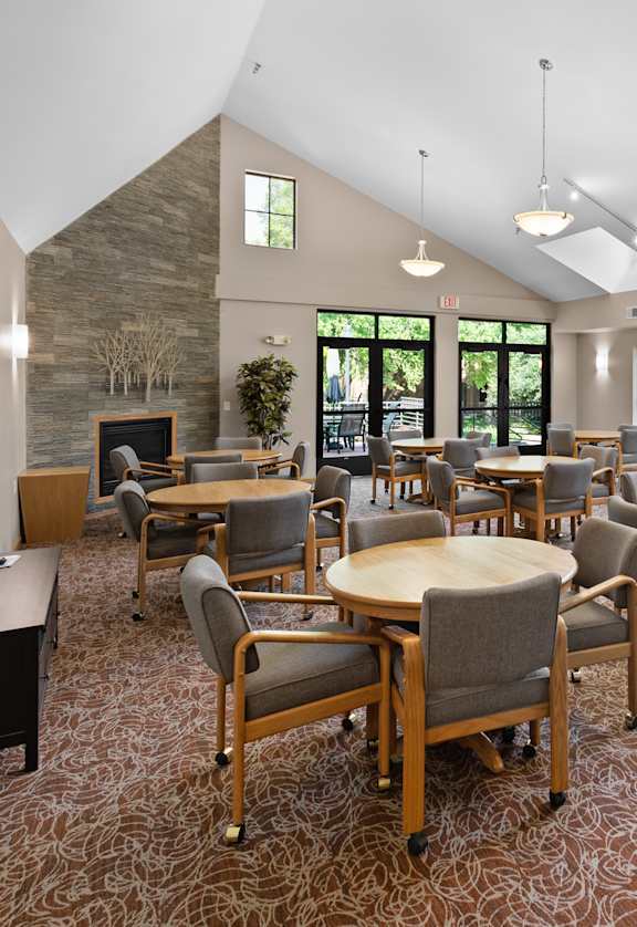 A room with tables and chairs and a stone wall.