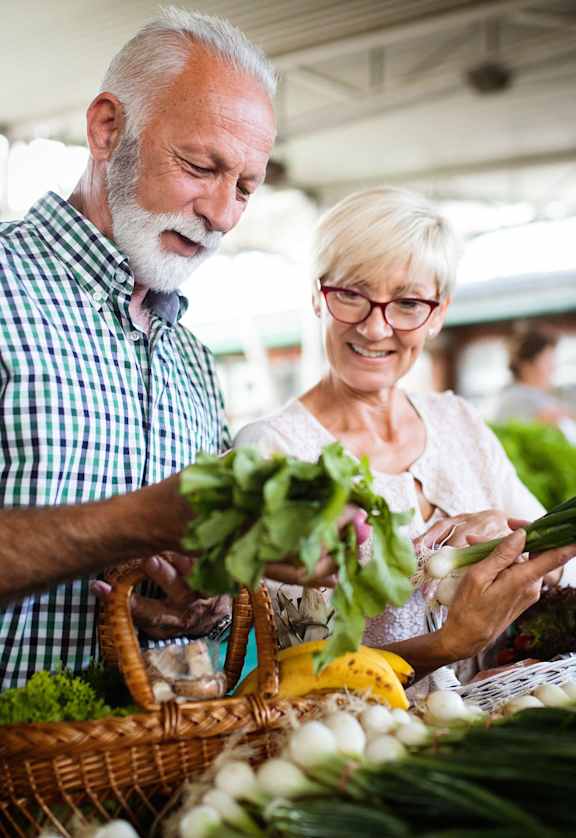 an older couple buying vegetables at a market
