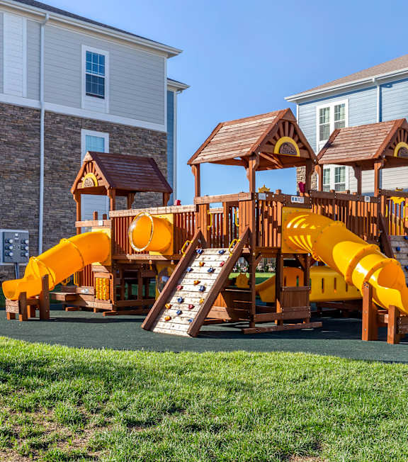 An outdoor playground with partial exterior views of the apartment complex buildings at Parkstone at Knightdale apartments in Knightdale, NC. 