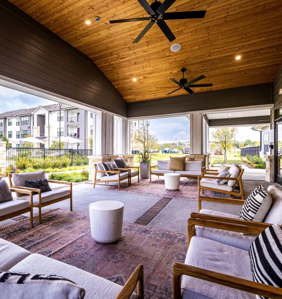 a covered patio with couches and chairs and a tv