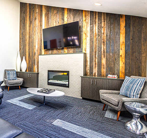 A modern living room with a fireplace and a flat screen TV mounted on the wall at Ellyson Apartment Homes in Tacoma, WA