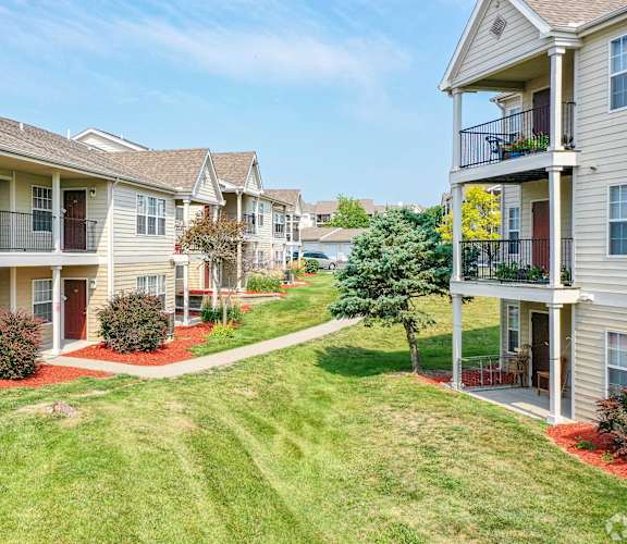 A sunny day at a residential apartment complex with green lawns and red flower beds.