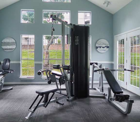 A home gym with a variety of equipment including a treadmill, weights, and a bench press.