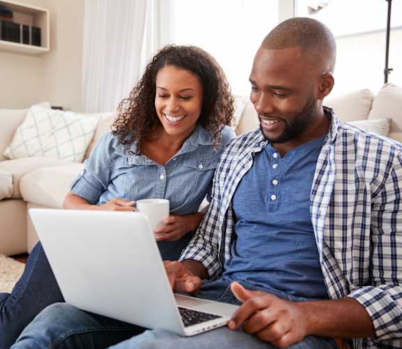 couple sitting on the floor using a laptop computer