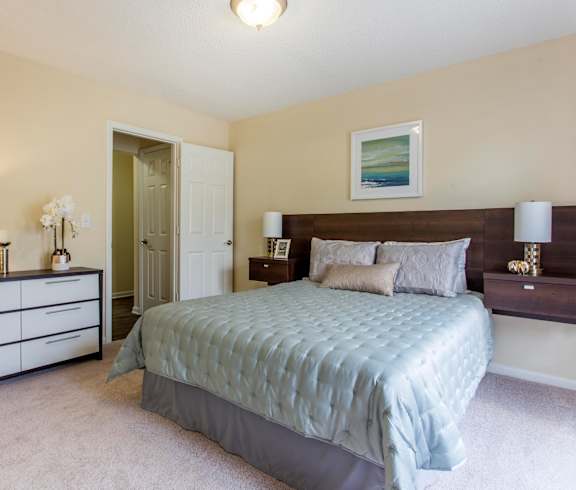a bedroom with a bed and dressers and a closet at Abbington Place Apartments, Greensboro