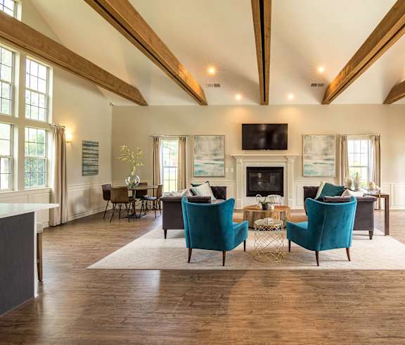 a living room with blue chairs and a fireplace at Abbington Place Apartments, Greensboro
