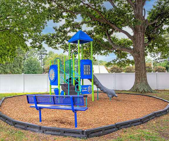 a playground with a swing set and a blue bench in front of a tree