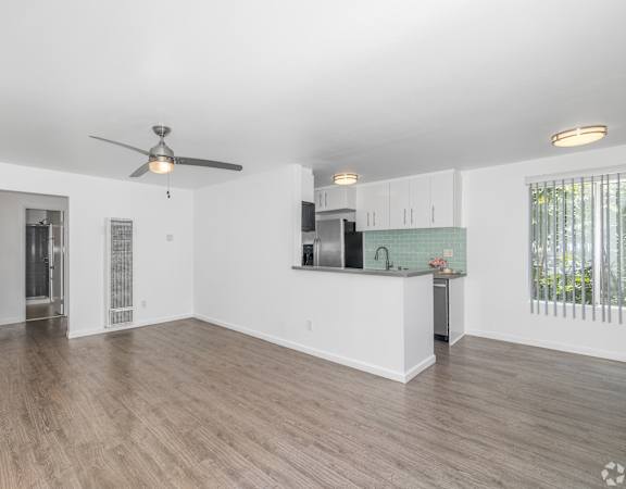 A spacious living room with a ceiling fan and hardwood flooring.