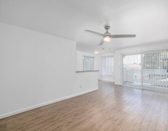 A spacious room with a ceiling fan and sliding glass doors.