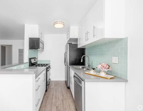 A kitchen with white cabinets and a green backsplash.