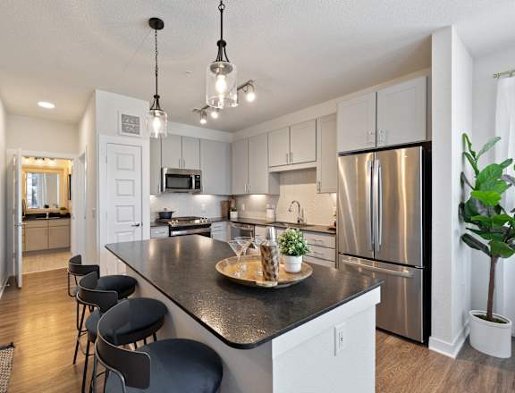 A kitchen with a black countertop and stainless steel appliances.