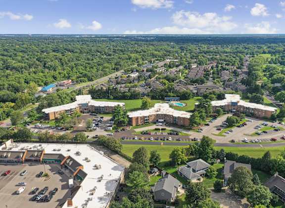 A bird's eye view of a large building surrounded by trees and a parking lot.